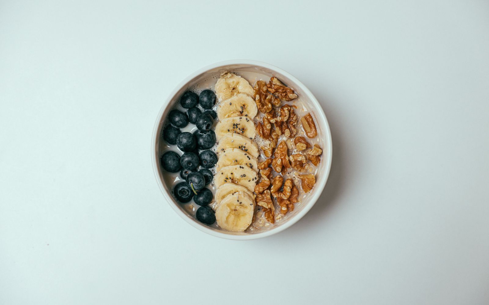 A bowl of slow oats topped with blueberries, banana, and walnuts