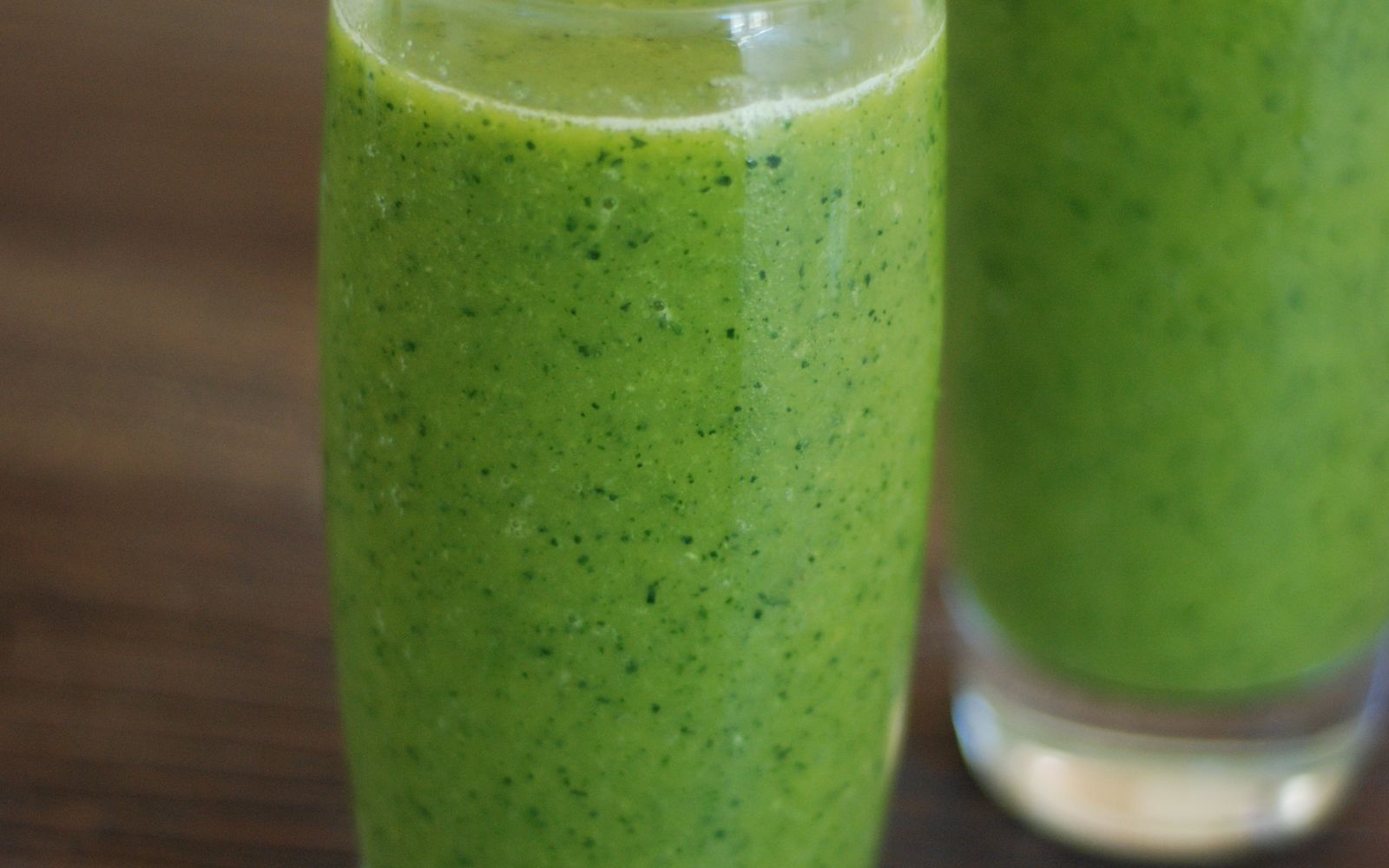 Two freshly mixed greens drinks in tall glasses