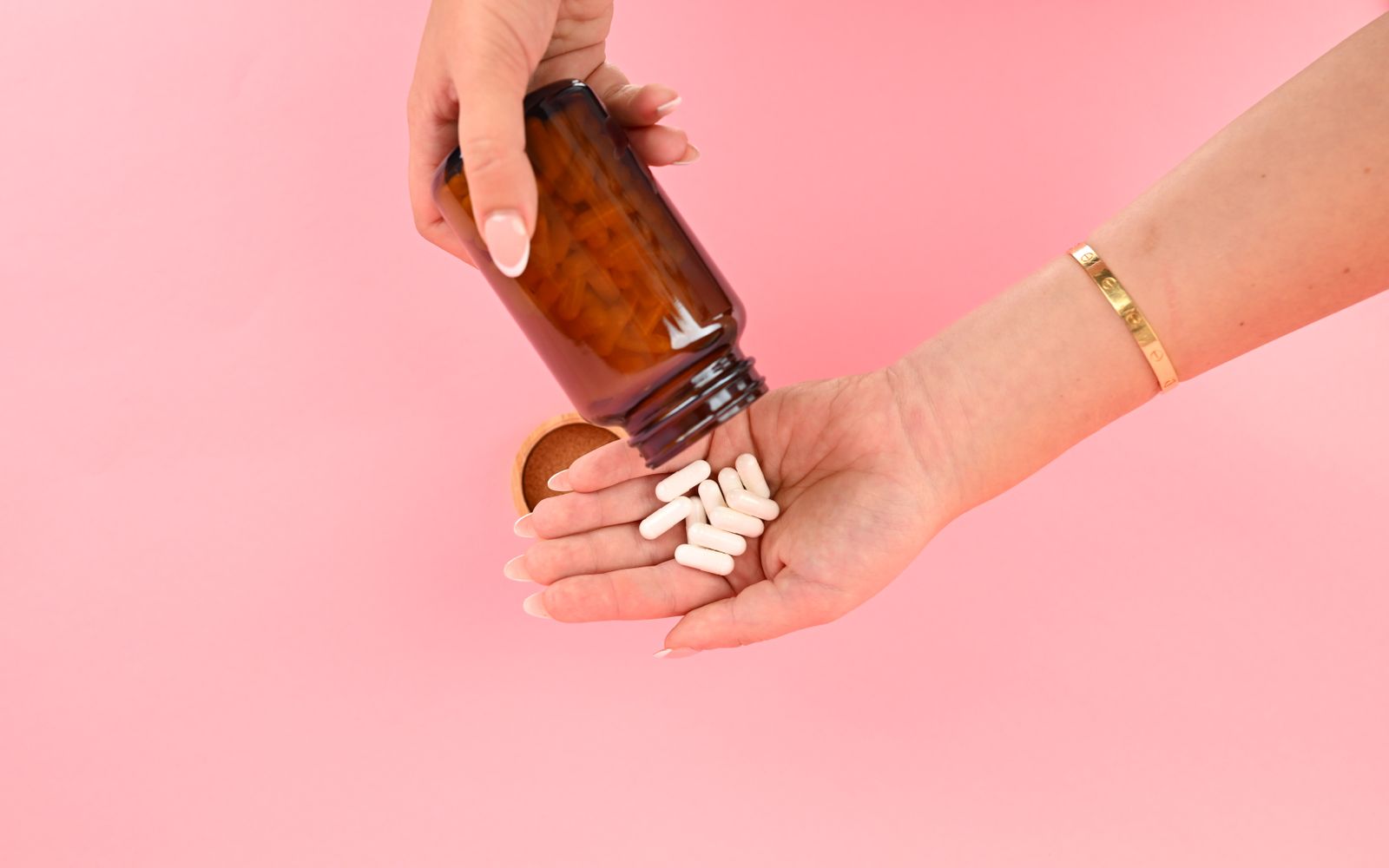 White NMN capsules poured from the bottle into an open palm