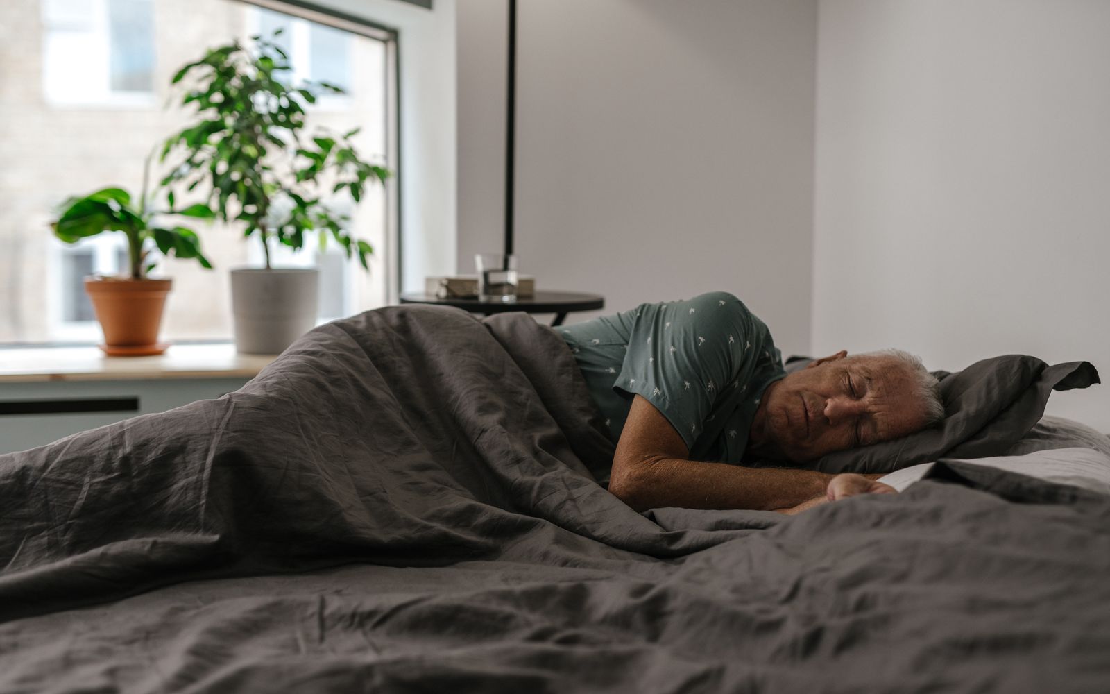 A man sleeps on his side in a bright bedroom with morning light